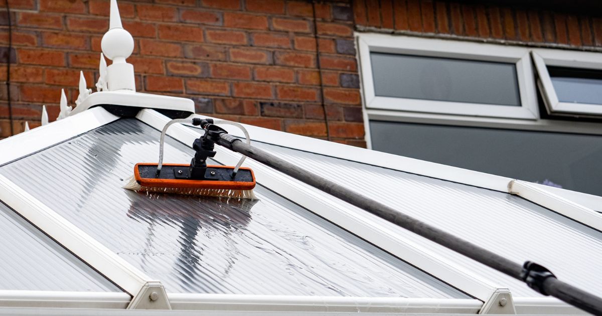 a upvc conservatory being cleaned by a window cleaner using a pole system